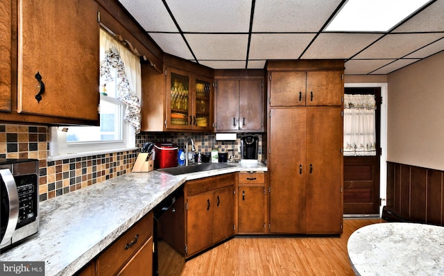 kitchen with black dishwasher, light hardwood / wood-style floors, a drop ceiling, and sink