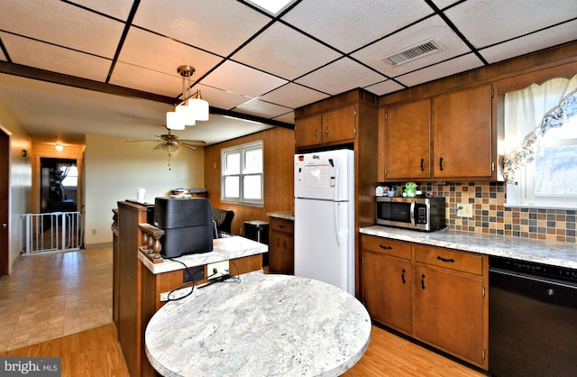 kitchen with decorative backsplash, light wood-type flooring, decorative light fixtures, dishwasher, and white fridge