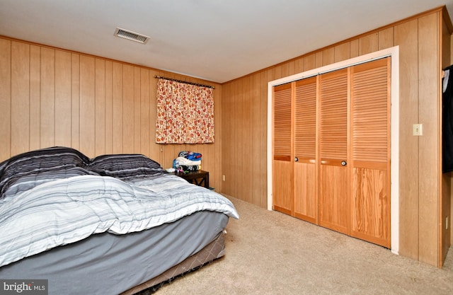 carpeted bedroom with wooden walls and a closet