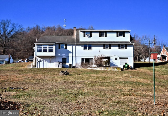 back of house featuring a garage and a lawn