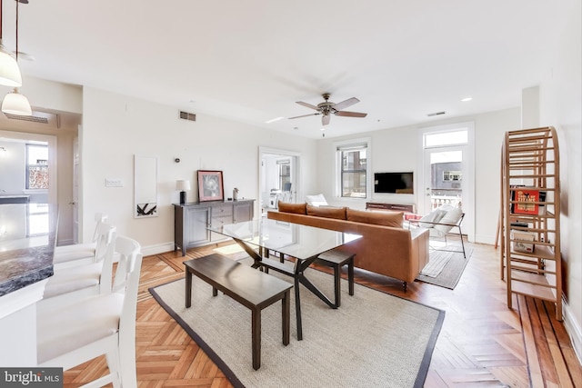 living room featuring ceiling fan, a wealth of natural light, and light parquet flooring