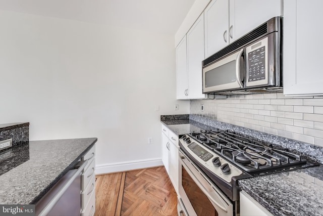 kitchen with white cabinets, dark stone counters, and stainless steel gas range oven