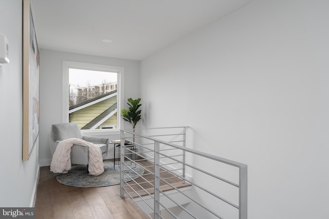 sitting room with baseboards, an upstairs landing, and wood finished floors