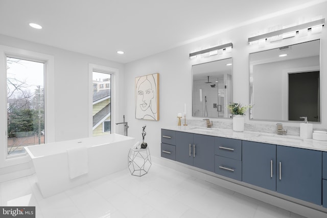 bathroom with a healthy amount of sunlight, a freestanding bath, and a sink