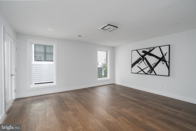 spare room featuring visible vents, baseboards, and dark wood-style flooring