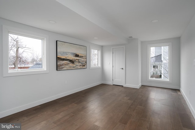 spare room featuring dark wood-style flooring and baseboards