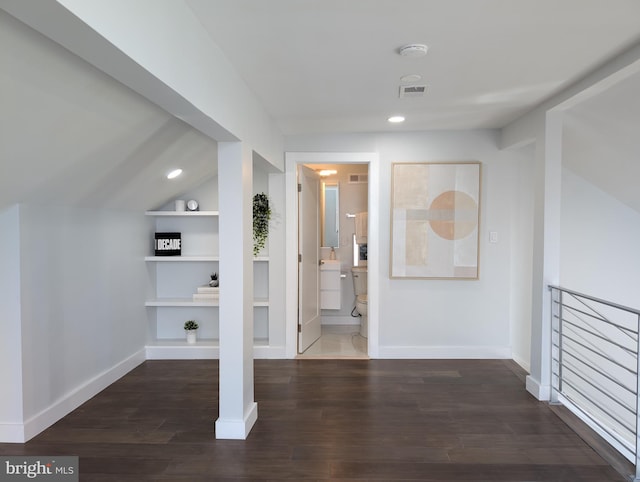 hall featuring dark wood-style floors, lofted ceiling, visible vents, and baseboards