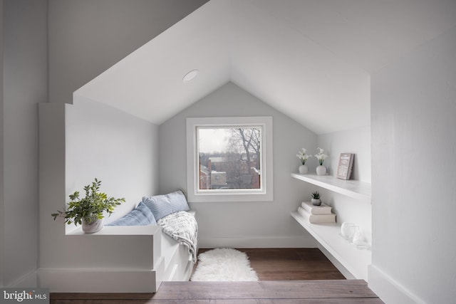 living area featuring baseboards, vaulted ceiling, and wood finished floors