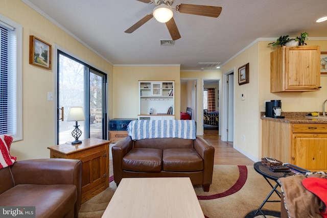 living room featuring ceiling fan, light hardwood / wood-style floors, sink, and crown molding