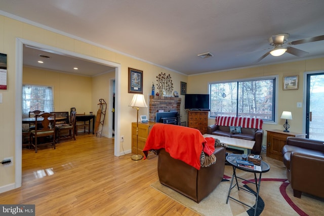 living room with light wood-type flooring, a wealth of natural light, ornamental molding, and ceiling fan