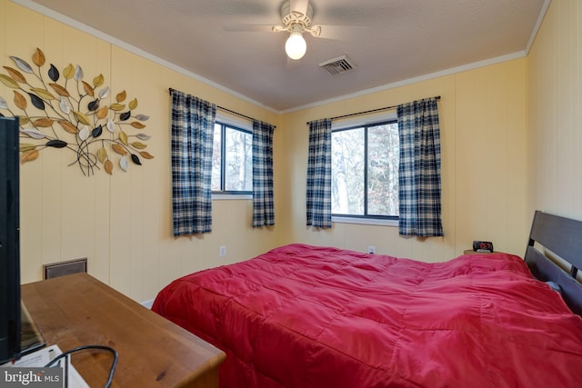 bedroom with a textured ceiling, wooden walls, ceiling fan, and crown molding