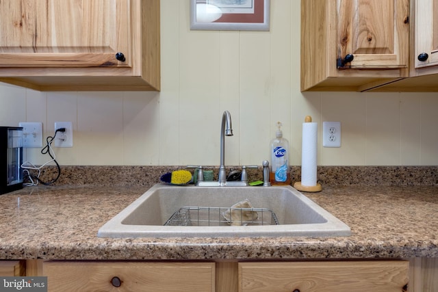 room details with light stone counters, sink, and light brown cabinets