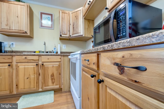 kitchen with white range oven, light brown cabinetry, sink, and light hardwood / wood-style floors