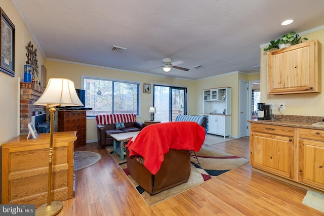 living room featuring a textured ceiling, light hardwood / wood-style floors, ceiling fan, and ornamental molding