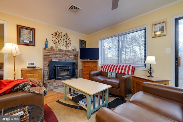 living room featuring hardwood / wood-style floors, a wood stove, crown molding, and a wealth of natural light