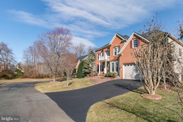 view of front facade with a balcony, driveway, a front lawn, a garage, and brick siding