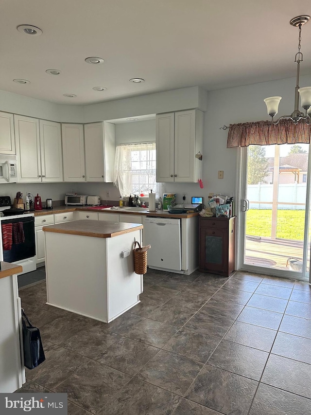 kitchen with pendant lighting, a center island, white appliances, sink, and white cabinetry