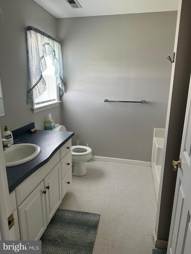 bathroom featuring vanity, a bath, and toilet