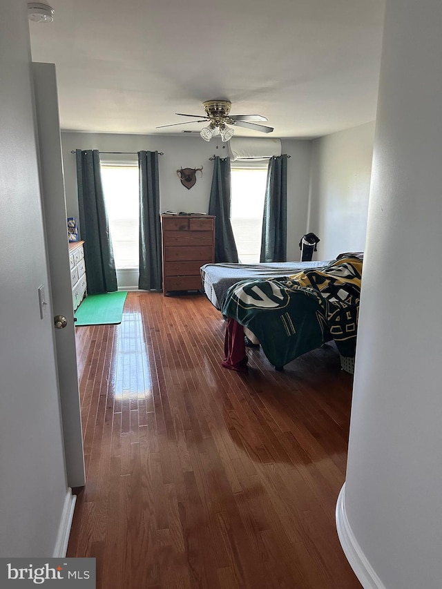 bedroom featuring hardwood / wood-style flooring, a wall unit AC, and ceiling fan