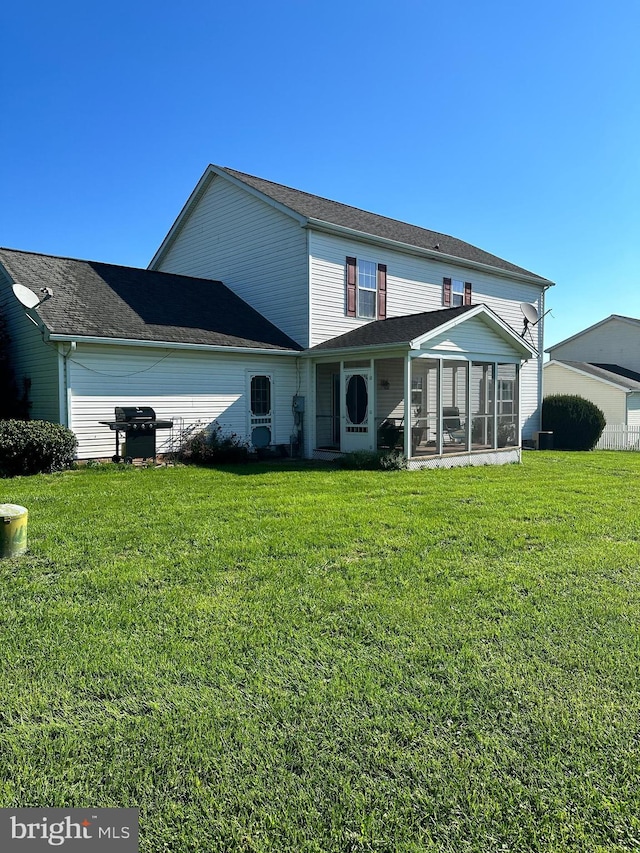 back of property with a sunroom and a lawn