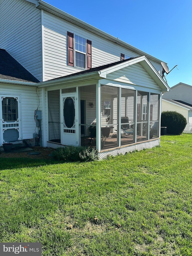 back of house with a lawn and a sunroom