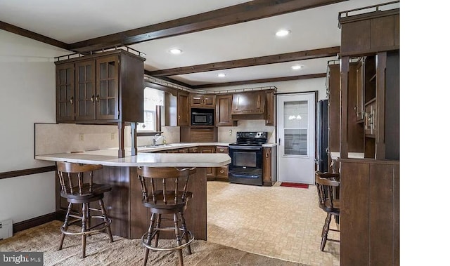 kitchen with black appliances, a kitchen breakfast bar, dark brown cabinetry, and kitchen peninsula