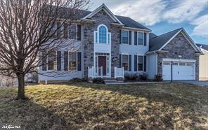 colonial inspired home featuring a garage and a front lawn