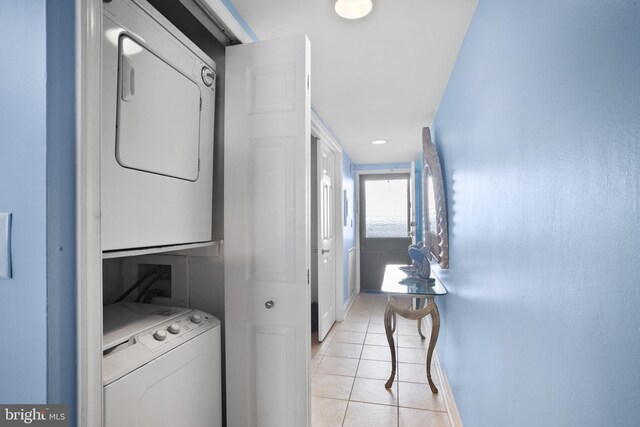 clothes washing area with light tile patterned floors and stacked washer / dryer