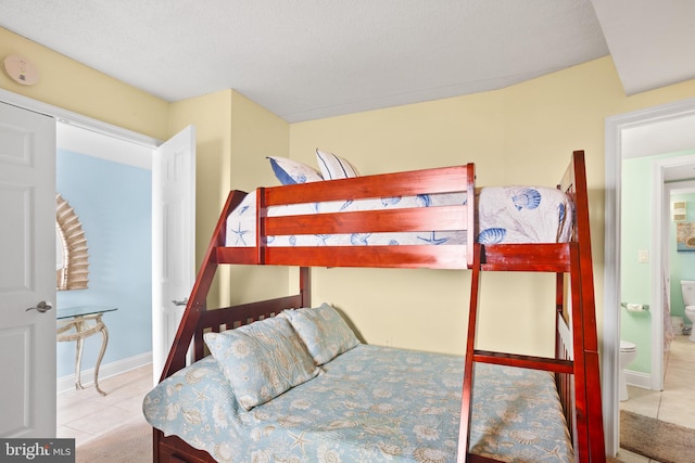 bedroom with connected bathroom and light tile patterned floors