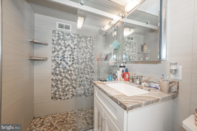 bathroom with vanity, a shower, and tile walls