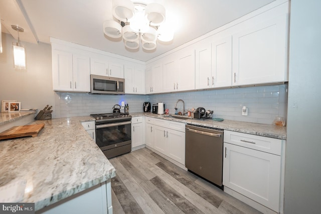 kitchen with sink, stainless steel appliances, light hardwood / wood-style flooring, decorative light fixtures, and white cabinets