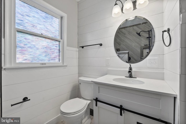 bathroom with vanity, toilet, and wooden walls