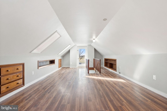 additional living space featuring vaulted ceiling with skylight and dark hardwood / wood-style floors