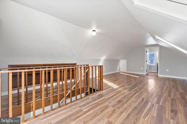 additional living space with hardwood / wood-style floors and lofted ceiling