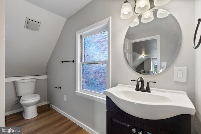 bathroom with hardwood / wood-style flooring, vanity, toilet, and vaulted ceiling