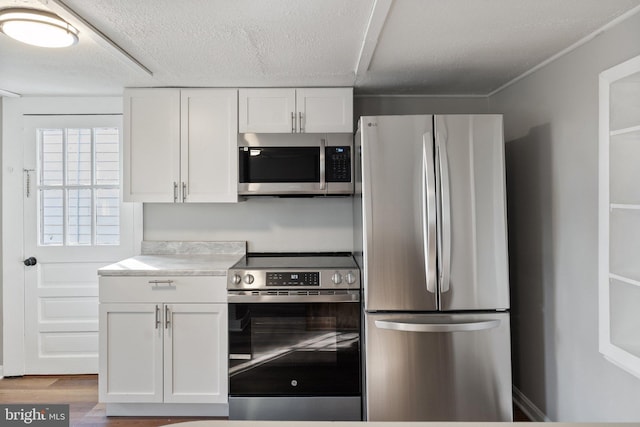 kitchen with white cabinetry, light hardwood / wood-style floors, a textured ceiling, and appliances with stainless steel finishes