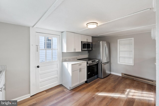 kitchen featuring white cabinets, a textured ceiling, a baseboard radiator, wood-type flooring, and stainless steel appliances