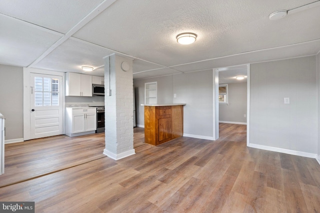 unfurnished living room featuring light wood-type flooring and a textured ceiling