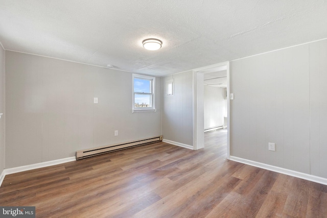 unfurnished room with baseboard heating, a textured ceiling, and hardwood / wood-style flooring