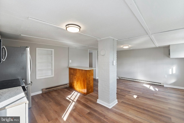 interior space with kitchen peninsula, baseboard heating, and dark wood-type flooring