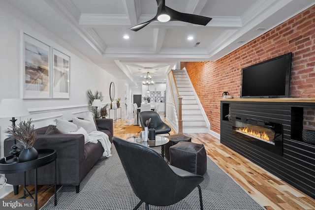 living room with coffered ceiling, ceiling fan with notable chandelier, hardwood / wood-style flooring, ornamental molding, and beamed ceiling