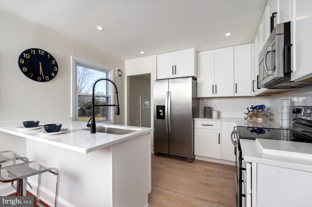 kitchen with a breakfast bar, white cabinetry, sink, and appliances with stainless steel finishes