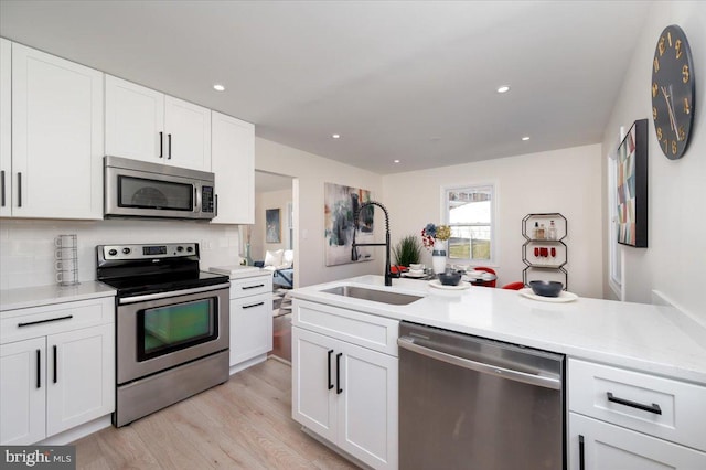 kitchen with sink, white cabinets, light hardwood / wood-style floors, and appliances with stainless steel finishes