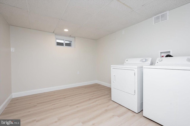 clothes washing area with light wood-type flooring and washer and clothes dryer