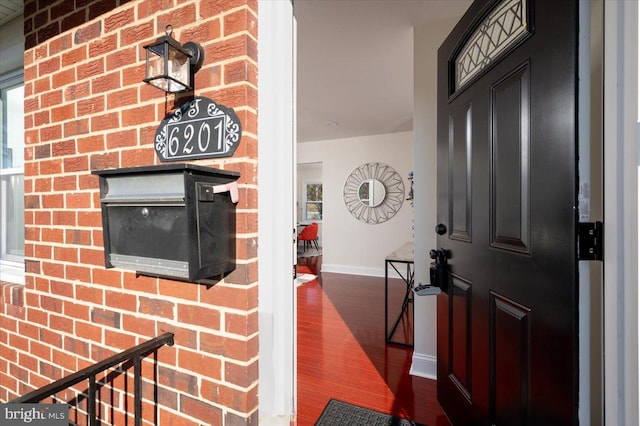 foyer entrance with dark hardwood / wood-style flooring and brick wall