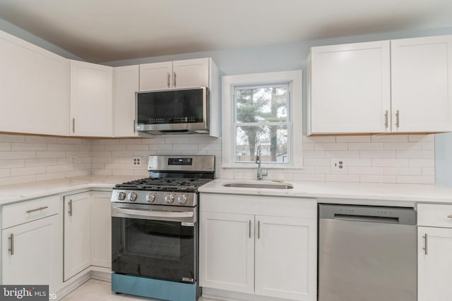 kitchen with white cabinets, backsplash, sink, and stainless steel appliances