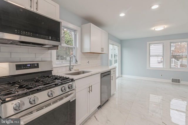 kitchen featuring backsplash, a wealth of natural light, white cabinetry, and stainless steel appliances