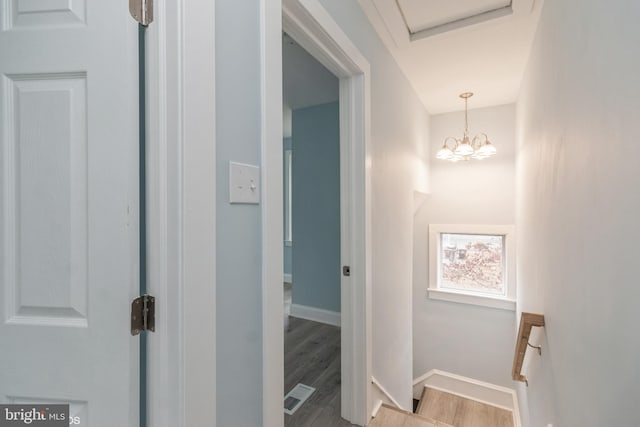 hall with light wood-type flooring and a notable chandelier