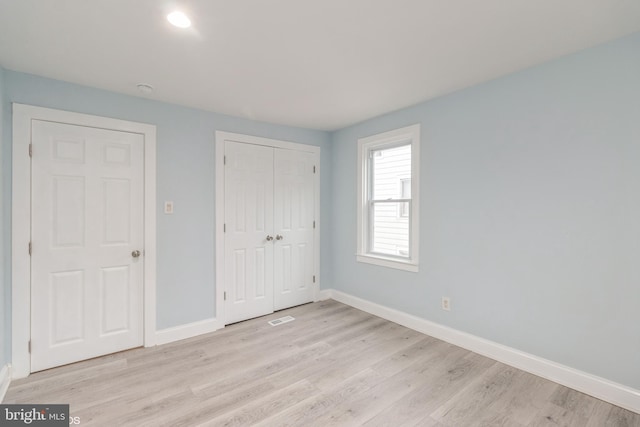 unfurnished bedroom featuring light hardwood / wood-style flooring and a closet