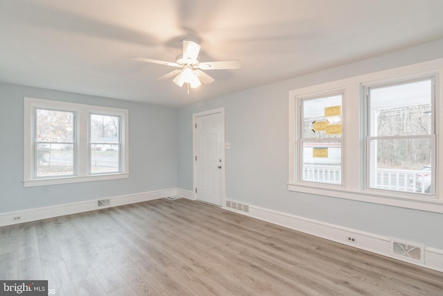 empty room with ceiling fan, a healthy amount of sunlight, and light hardwood / wood-style floors